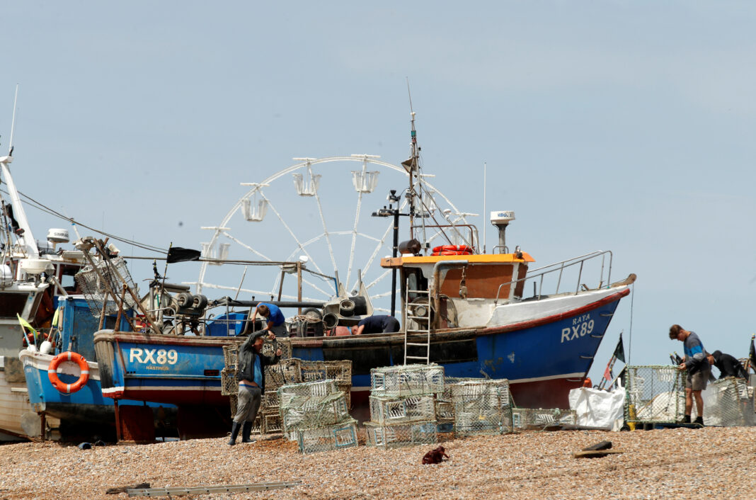 FOTO DE ARCHIVO: Un barco pesquero y varios pescadores en la playa de Hastings, Reino Unido, el 9 de junio de 2020. REUTERS/Matthew Childs