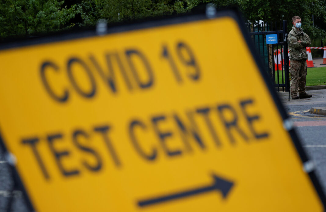 FILE PHOTO: A soldier wearing a protective face mask stands near a sign at the entrance of a testing centre, as Blackburn with Darwen Council imposes local restrictions in an effort to avoid a local lockdown being forced upon the area, amid the coronavirus disease (COVID-19) outbreak, in Blackburn, Britain, July 15, 2020. REUTERS/Phil Noble/File Photo