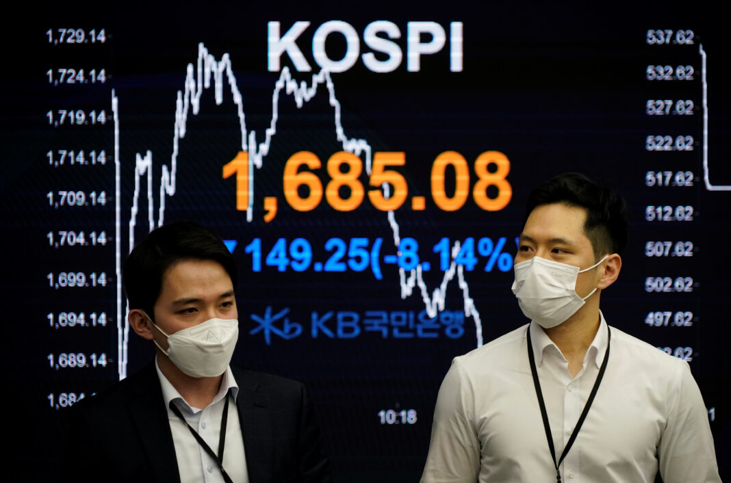 FOTO DE ARCHIVO. Operadores bursátiles pasan junto a un tablero electrónico que muestra el índice de precios de las acciones de Corea (KOSPI) en una sala de operaciones de un banco en Seúl, Corea del Sur. 13 de marzo de 2020. REUTERS/Kim Hong-ji