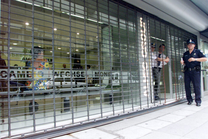 Foto de archivo - Un oficial de policía se encuentra junto a la puerta de una casa de cambio cerrada, en el centro financiero de Buenos Aires, Argentina. Jan 2, 2002. REUTERS/Andres Stapff