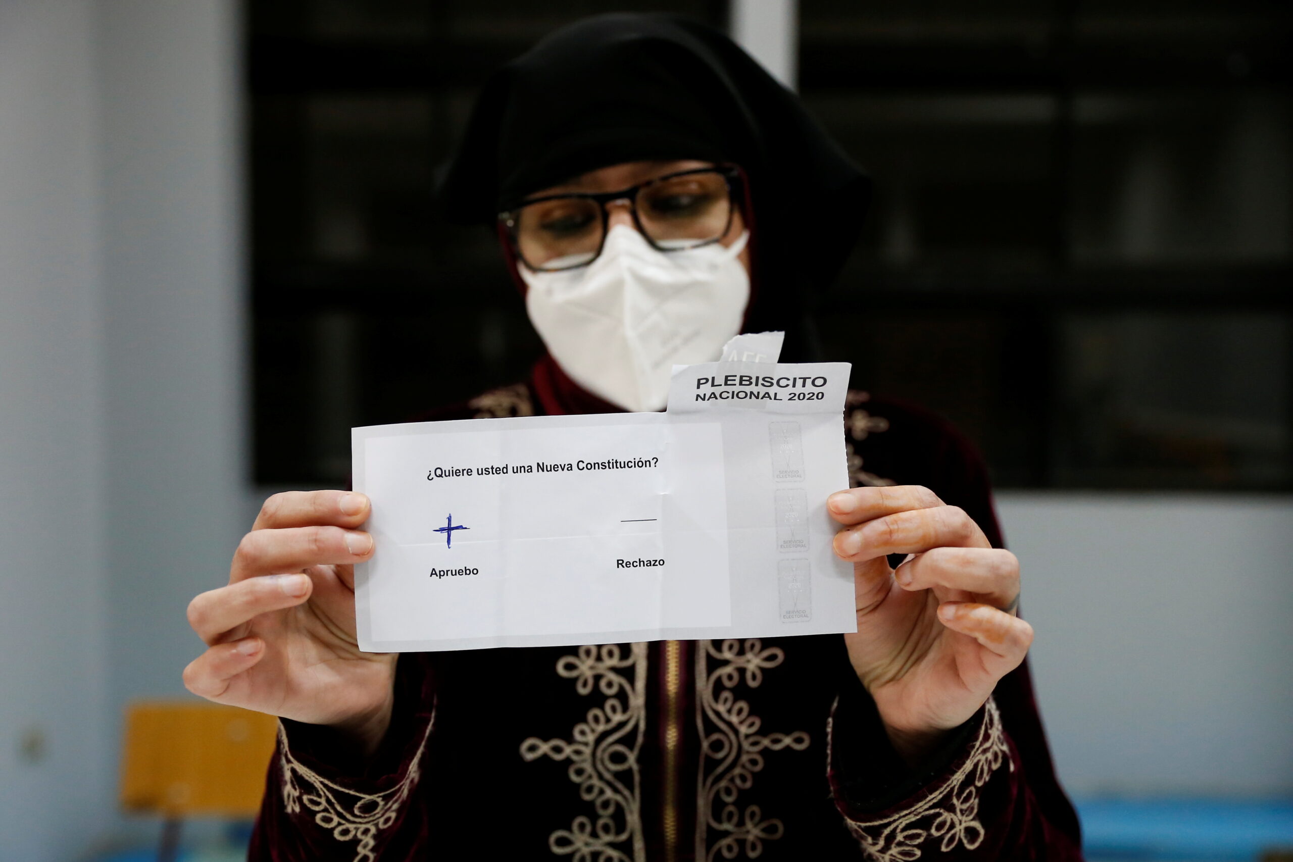 Una trabajadora electoral que lleva una máscara protectora muestra un voto durante un referéndum sobre una nueva constitución, en Valparaíso, Chile. 25 de octubre de 2020. REUTERS/Rodrigo Garrido