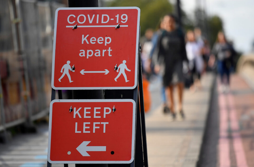 FOTO DE ARCHIVO: Peatones caminan cerca de las pancartas con avisos de salud pública en Londres, Reino Unido, el 11 de septiembre de 2020. REUTERS/Toby Melville