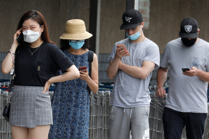 FILE PHOTO: People wear protective face masks outside at a shopping plaza after New Jersey Governor Phil Murphy said he would sign an executive order requiring people to wear face coverings outdoors to prevent a resurgence of the coronavirus disease (COVID-19), in Edgewater, New Jersey, U.S., July 8, 2020. REUTERS/Mike Segar