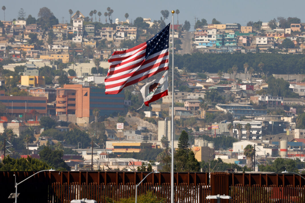 FOTO DE ARCHIVO. La bandera del estado de California y la de Estados Unidos ondean junto al muro fronterizo cerca de Tijuana, México, en San Diego, California, Estados Unidos. 14 de agosto de 2020. REUTERS/Mike Blake
